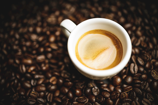 A cup of espresso coffee with roasted coffee beans on a white background. Top view