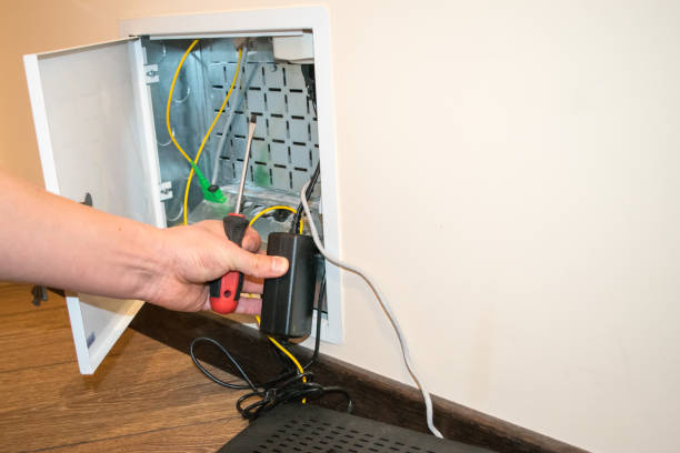 istock The router box is open, the human hand holds a screwdriver, there is a black router next to it 1291183521