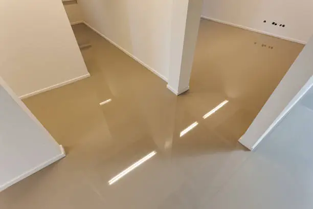 An indoor floor with a freshly added coating layer to create a synthetic cast floor installation.