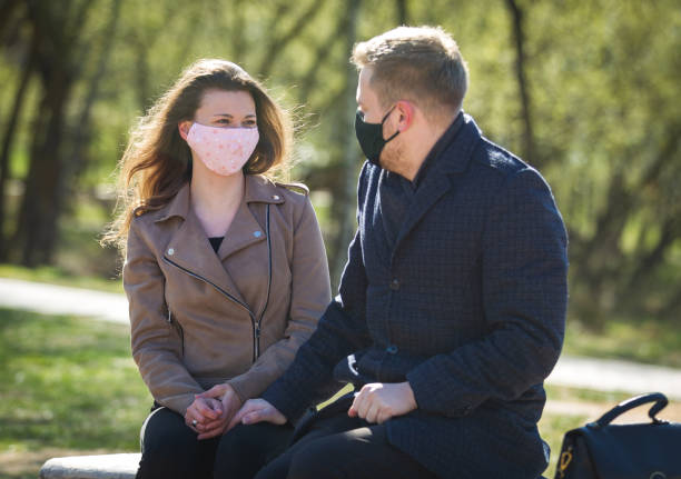 istock Masked young couple walking in the park 1291185059