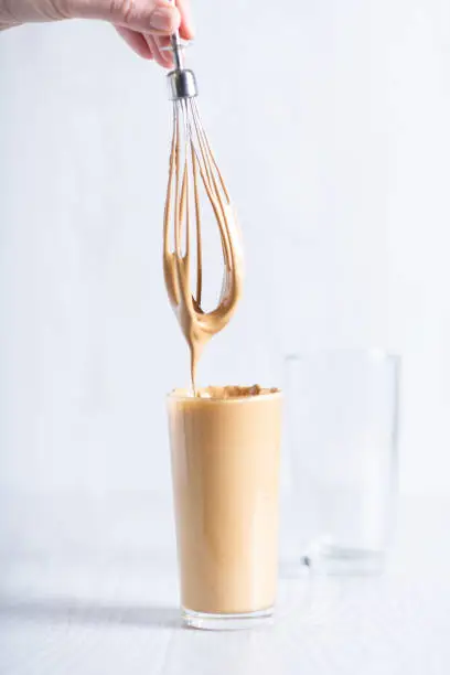 ready-made drink dalgon from instant coffee, sugar, water and milk. Korean fluffy creamy whipped coffee. Cold dalgonacoffee coffee in a glass on a light background. Iced coffee..