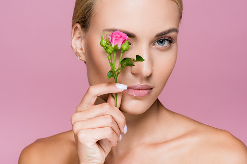 beautiful blonde woman with perfect skin and rose flower isolated on pink