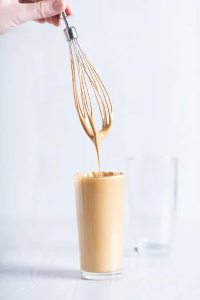 ready-made drink dalgon from instant coffee, sugar, water and milk. Korean fluffy creamy whipped coffee. Cold dalgonacoffee coffee in a glass on a light background. Iced coffee..