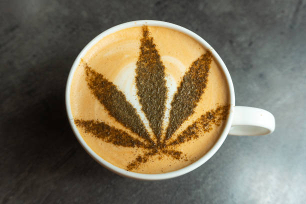 Photo of coffee in a mug with cannabis leaf on the top of it. stock photo