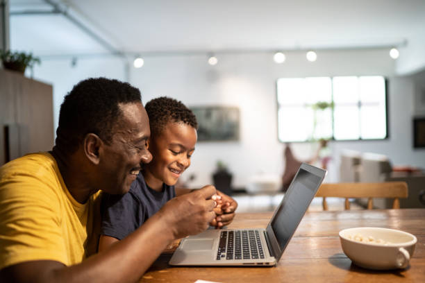 istock Grandfather using laptop with grandson at home 1291187733