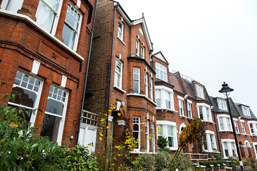 Color image depicting typical red brick townhouses on a residential street in the affluent area of Hampstead in London, UK.