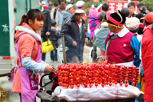 Lijiang, China - March 8, 2012: Street vendor with tanghulu in Lijiang Old Town, the UNESCO Heritage Site and popular tourist destination in Yunnan, China.
