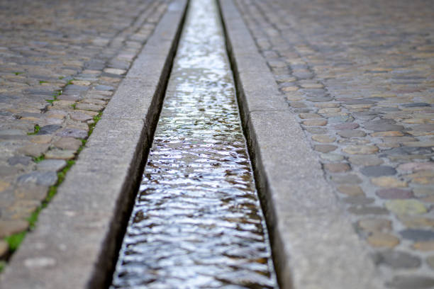 Water stream in formalised rill in pavement of the street. Famous small water-filled runnels - Bächle, in the city of Freiburg, Germany