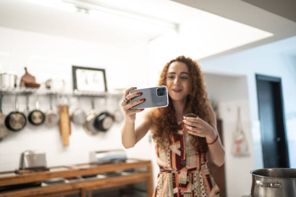 istock Transgender woman doing a video call or vlogging with mobile phone while cooking at home 1291190862