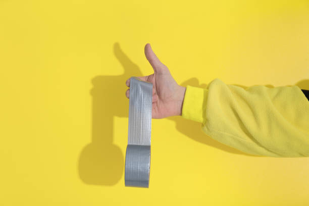 la mano maschile in kugurumi giallo tiene i bastoncini del nastro ultimate gray - pantone 2021 foto e immagini stock