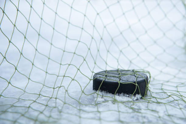 hockey puck in the goal net close-up - ice hockey hockey puck playing shooting at goal imagens e fotografias de stock