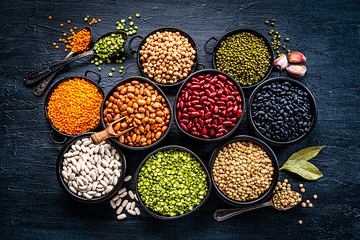 Food Backgrounds: large variety of dried beans, legumes and cereals shot from above on dark table. The composition includes green, yellow and brown lentils, chick-peas, black beans, Pinto beans, Kidney beans, fava beans, mung beans, white beans, soy beans among others. High resolution 42Mp studio digital capture taken with SONY A7rII and Zeiss Batis 40mm F2.0 CF lens