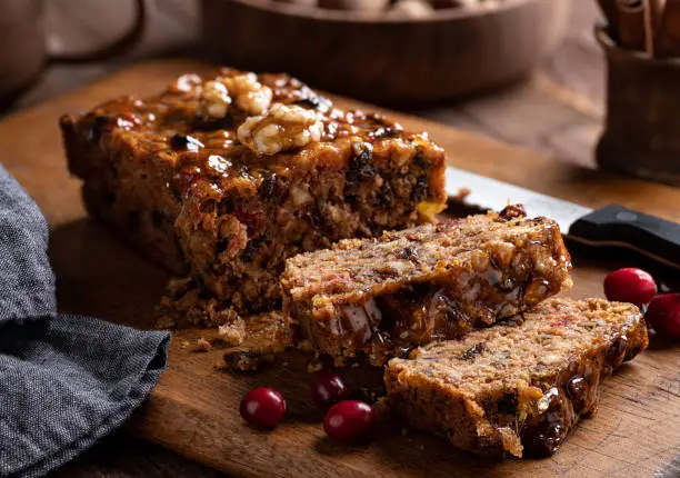 Fruitcake loaf sliced on a rustic wooden cutting board