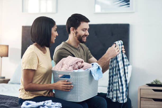 Teamwork lightens the load Shot of a young couple doing laundry together at home laundry husband housework men stock pictures, royalty-free photos & images