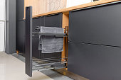 Pull-out kitchen drawer in the kitchen for towels, jars. Modern beautiful kitchen in gray, wooden tones