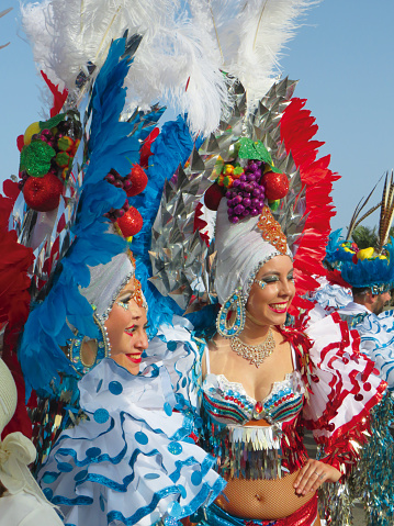 Tenerife, February 2020: Carnival youth with feather headdresses and tropical fruits. Small parade of dancers in festival costumes who celebrate Carnival in the streets
