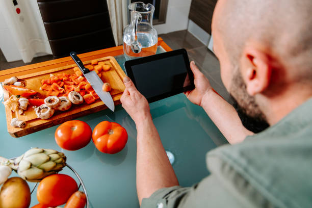 istock looking at the recipe on the tablet in the kitchen 1291197592