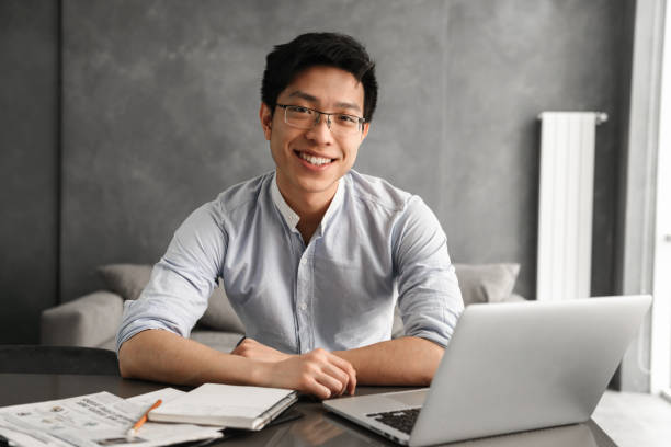 istock Portrait of a friendly young asian man using laptop 1291200367