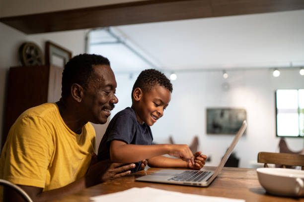 istock Grandfather using laptop with grandson at home 1291201840