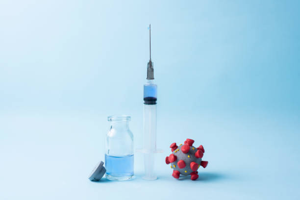 istock Coronavirus model, a syringe with vaccine and vaccine bottle on blue background. 1291202018