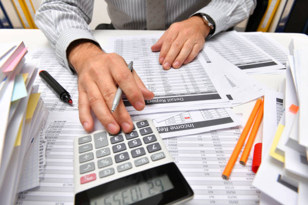 istock business concept - businessman working with reports in office, table and workspace close view, analyzing financial data, writes and counts 1291206676