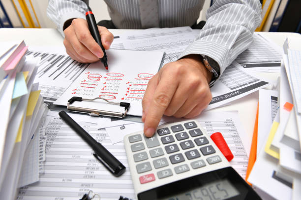 istock business concept - businessman working with reports in office, table and workspace close view, analyzing financial data, writes and counts 1291206958