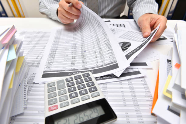 istock business concept - businessman working with reports in office, table and workspace close view, analyzing financial data, writes and counts 1291207819