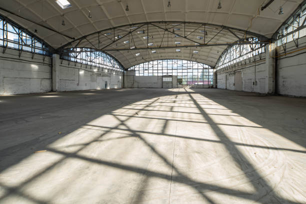istock Huge empty industrial warehouse. White interior. Unique architecture. Hemispherical reinforced concrete load bearing roof with windows. Shadow of construction on floor. 1291208348