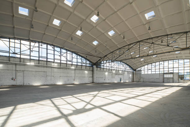 istock Huge empty industrial warehouse. White interior. Unique architecture. Hemispherical reinforced concrete load bearing roof with windows. Shadow of construction on floor. 1291208350