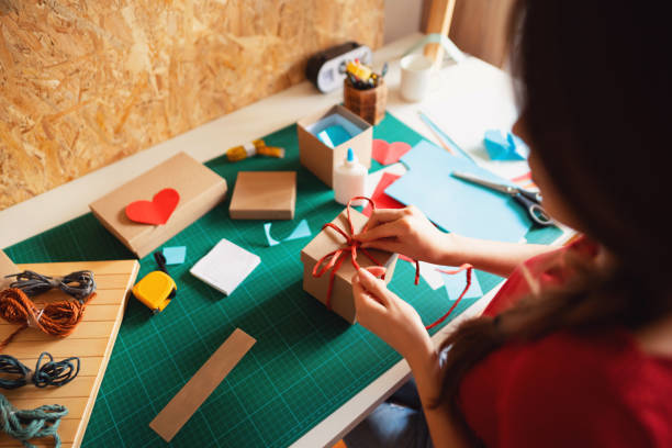 istock Woman wrapping cardboard gift box 1291209814