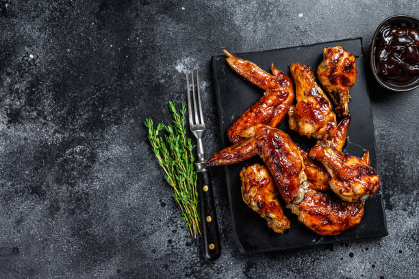 istock Hot Barbecue chicken wings with sauce bbq. Black background. Top view. Copy space 1291211165