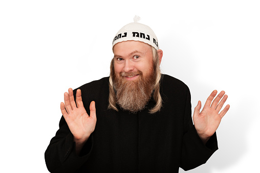 Smiling bearded Orthodox jewish man isolated on white background. Cheerful charismatic Jew with sidelocks in white yarmulke showing palms and hinting that he has nothing to do with it. The inscription in Hebrew language on the kippah is Na Nach Nachma Nachman Meuman translates as Rabbi Nachman from Uman