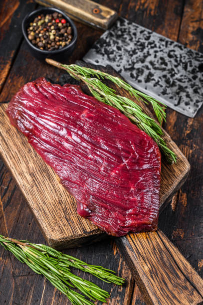 istock Venison raw meat steak on a cuuting board with rosemary. Black background. Top view 1291212923
