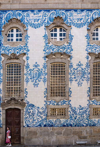 Porto, Portugal - 08/21/2019: Traditional Portuguese tiles of Carmo church. Girl modeling in front of the door. Beautiful art. Porto, Portugal