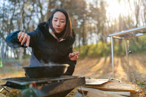 istock Young woman preparing breakfast at camp site in winter 1291216898
