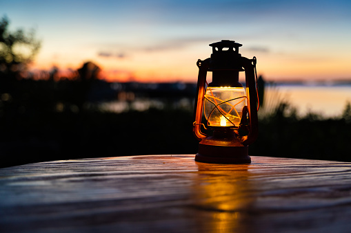 Antique lantern on a table outdoor with the sea on the back