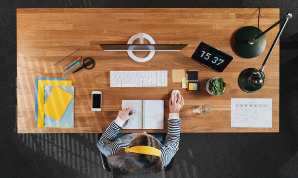 istock Top view of female student working on computer at desk at home. 1291218598
