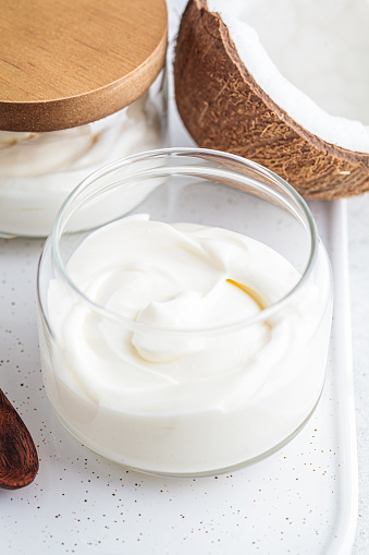 Vegan coconut yogurt in glass jars, white background.