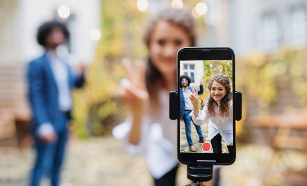 ungt par gör video med smartphone utomhus på gatan, tik tok koncept. - påverkare bildbanksfoton och bilder