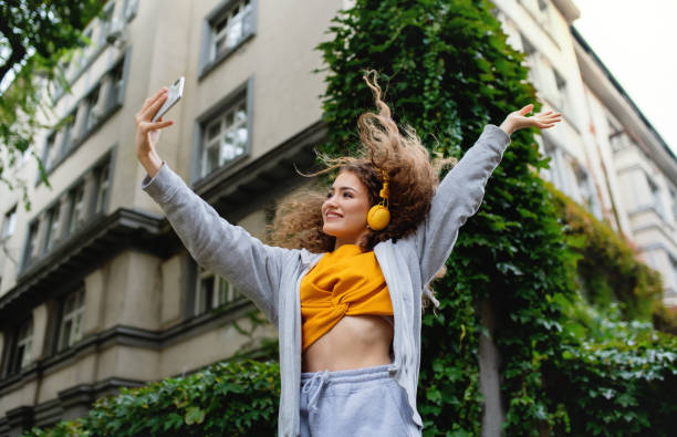 ung kvinna med smartphone dans utomhus på gatan, tik tok koncept. - påverkare bildbanksfoton och bilder