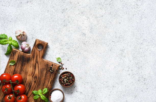 istock Brown cutting board with spices and vegetables on a light, a concrete kitchen table. Layout. 1291229563