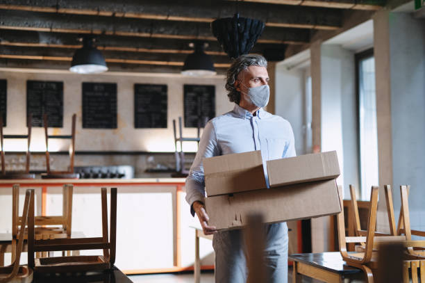 istock Frustrated owner carrying boxes in closed cafe, small business lockdown due to coronavirus. 1291231049