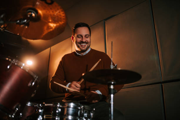 Portrait of a smiling man playing playing drums in studio.