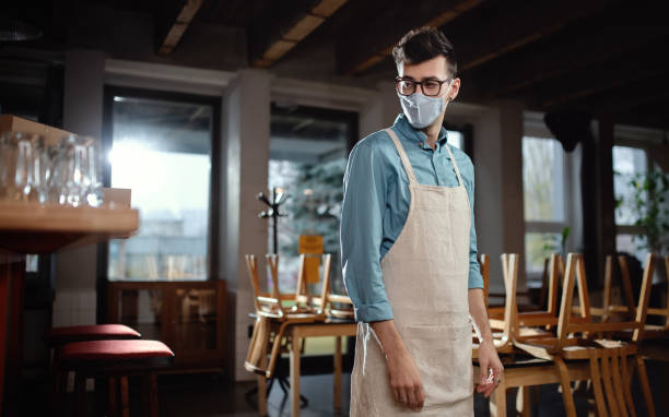 istock Frustrated waiter standing in closed cafe, small business lockdown due to coronavirus. 1291232749