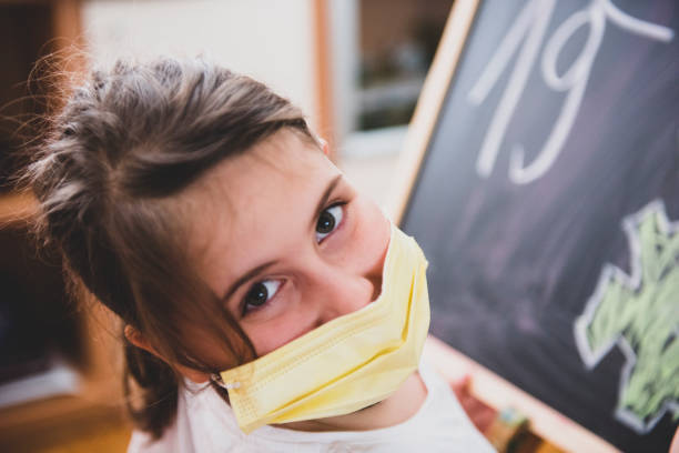 istock Cute little girl is drawing on blackboard 1291234340