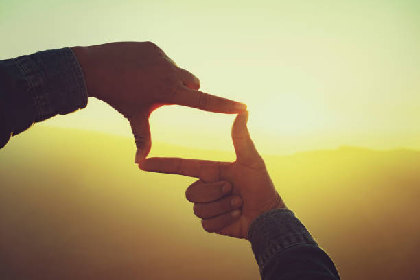 istock woman hand framing view distant over sunset. business concept 1291236380