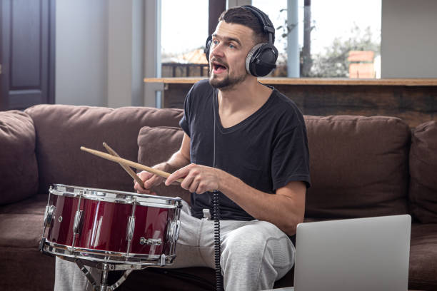 istock A young man with headphones learns to play the drum using online lessons. 1291237646