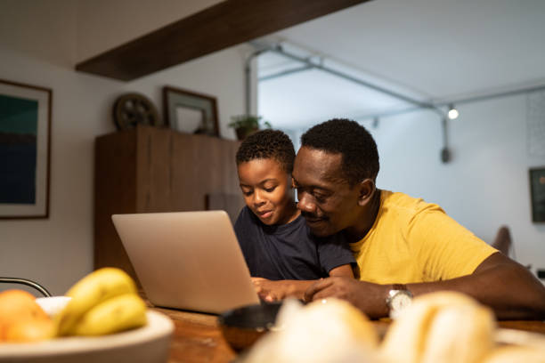 grandfather helping grandson studying or working at home - grandparent using computer laptop dining table imagens e fotografias de stock