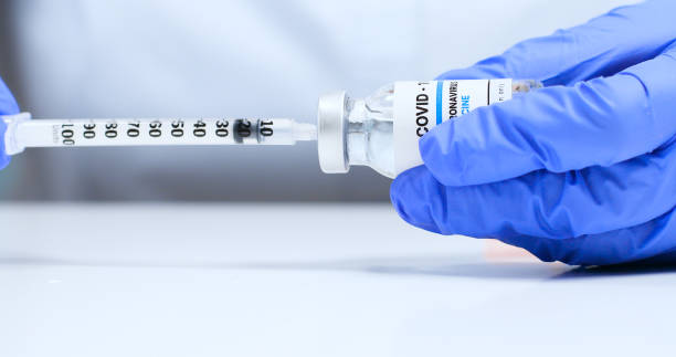 Female doctor hands in blue medical gloves with transparent liquid coronavirus vaccine bottle and syringe for injection in the laboratory. Research and development of new cure for diseases Close-up of female doctor hands in blue medical gloves with transparent liquid coronavirus Sars-Cov-2 vaccine bottle and syringe for injection in the laboratory. Research and development of new cure for diseases covid 19 vaccine photos stock pictures, royalty-free photos & images
