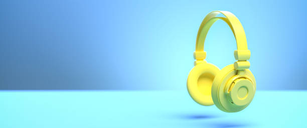 istock Music concept: A yellow headphone against a blue background with shadow. Web banner size with copy space - selective focus on foreground 1291238592